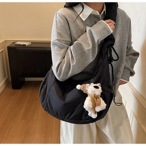 Detail of a black oversized dumpling crossbody bag with a cute bear plush pendant