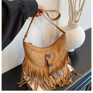 Dettaglio delle frange in pelle scamosciata caramello e fibbia vintage su borsa boho