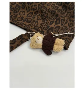 Detail of leopard print tote bag with a cute teddy bear plush charm and metal ring
