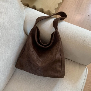 Détail d'un grand sac cabas en daim marron à imprimé léopard posé sur un canapé blanc