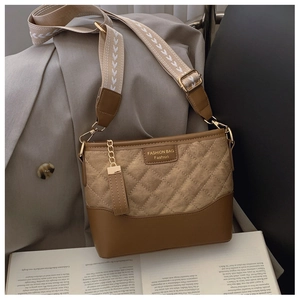 Detail of tan quilted bucket bag with patterned canvas strap and gold chain accent