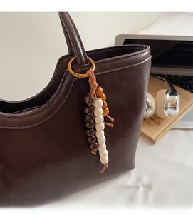 Détail d'un bijou de sac rétro en perles de bois sur un sac cabas en cuir marron
