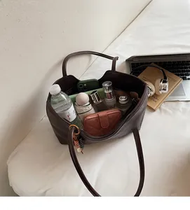 Intérieur spacieux du cabas tressé marron foncé contenant les essentiels du quotidien