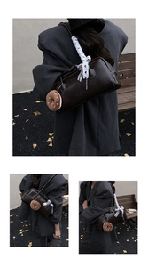 Detail of dark brown leather underarm bag with lace ribbon and plush donut pendant charm