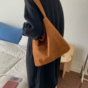 Détail d'un grand sac hobo léopard en suédine porté avec un long manteau en laine
