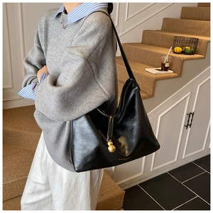 Détail d'un sac cabas en cuir noir avec pendentif gourde doré et logo gravé