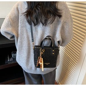 Detail of black leopard print crossbody bag with wooden bead tassel and metal buckle