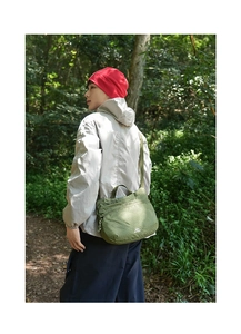 Close-up of army green nylon messenger bag with ripstop texture in outdoor forest setting