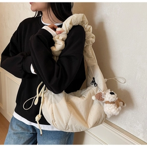 Detail of quilted white cloud bag with scrunchie style strap and plush puppy charm