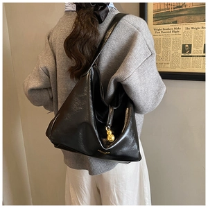 Détail du sac à bandoulière noir brillant avec breloque dorée et imprimé mode