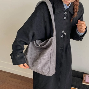 Détail d'un grand sac hobo gris à imprimé léopard porté avec un manteau d'hiver en laine