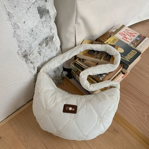 Detail of cream crescent bag featuring heart quilting and pearl embellished leather patch