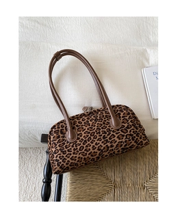 Top view of a leopard print baguette bag with brown leather handles on a chair