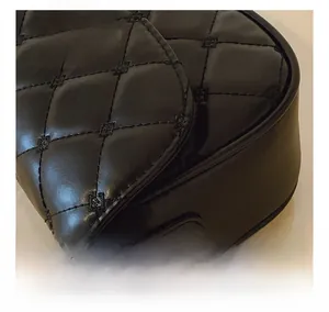 Detail of black quilted leather with a gold metal twist lock on a chain shoulder bag