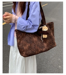 Close-up of a large leopard print tote bag with a cute brown teddy bear keychain accessory