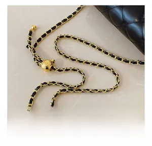 Detail of black quilted leather with adjustable gold ball chain strap on the bag