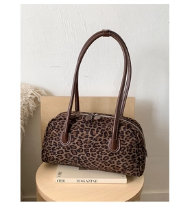 Detail view of leopard print baguette bag with brown leather handles and double zipper design