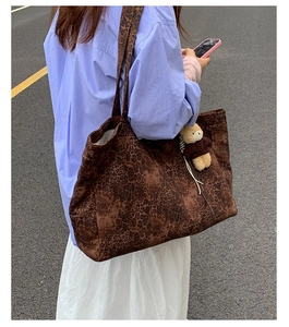 Detail of a large leopard print tote bag with bear charm worn by a model in street style