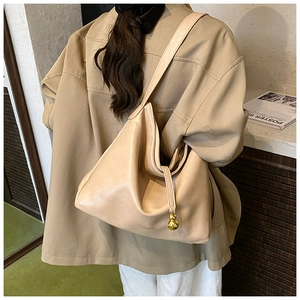 Détail du sac cabas beige minimaliste avec pendentif gourde dorée et bandoulière élégante