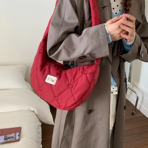 Detail of red heart-quilted down shoulder bag with 'So big' label on dark coat