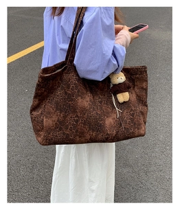 Large leopard print tote bag with plush bear charm worn by a model in a street setting