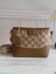 Chic quilted brown bucket bag with gold chain and canvas strap on marble surface
