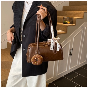 Détail du sac baguette marron vintage avec breloque donut en peluche et nœud en dentelle