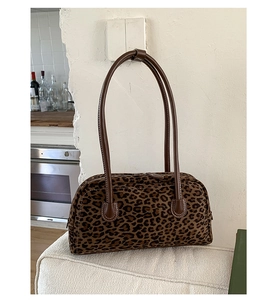 Detail of leopard print baguette bag with long brown leather straps in a home setting
