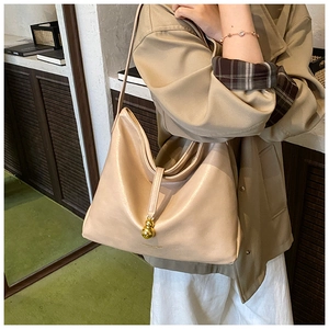 Gros plan du sac porté épaule beige minimaliste avec un pendentif en métal doré unique
