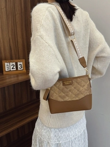 Quilted bucket bag in brown with wide embroidered strap shown on model for daily commute