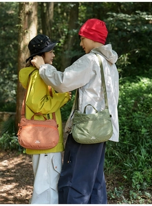 Gros plan sur les sacs bandoulière en nylon imperméable orange et vert avec poignée