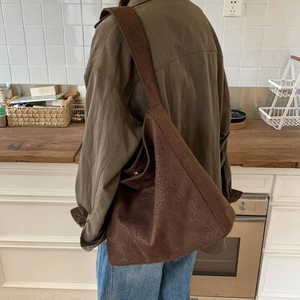 Grand sac bandoulière marron en daim avec texture animale porté par un mannequin rétro
