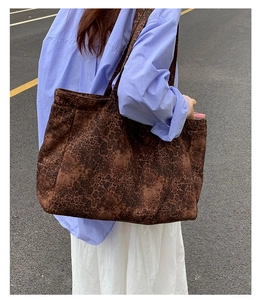Detailed street style view of a large leopard print tote bag worn over the shoulder