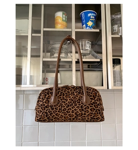 Detail of leopard print faux fur texture and brown leather handle on a baguette bag