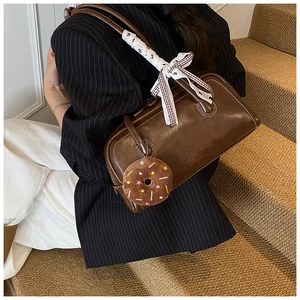 Détail d'un sac à main en cuir marron vintage avec surpiqûres et ruban de soie écossais