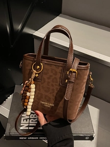 Brown leopard print suede tote bag with leather handles and beaded tassel on steps