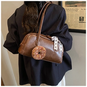 Sac baguette vintage marron avec breloque donut en peluche et ruban à pois sur l'anse