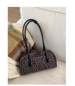 Detailed close-up of leopard print baguette bag on a beige knit sweater and sofa
