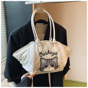 Dettaglio della borsa tote trapuntata con bordo in pelliccia e ricamo di gatto su blazer