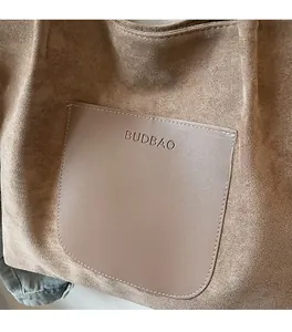 Close-up detail of the brown suede material and leather pocket on a large tote bag
