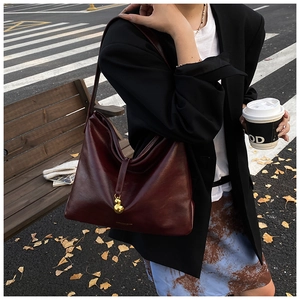 Détail du sac hobo en cuir rouge vin avec un pendentif décoratif en forme de gourde