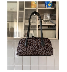 Detailed view of leopard print baguette bag with black leather handles and white stitching