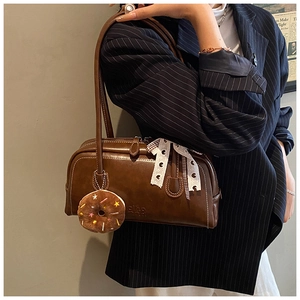 Détail du sac baguette vintage marron avec pendentif donut et ruban à pois élégant