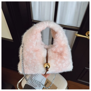 Détail d'un sac à main en fausse fourrure rose et blanche avec boule dorée et chaîne argent