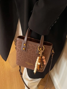 Leopard embossed dark brown bucket bag with gold rivets and beaded tassel charm