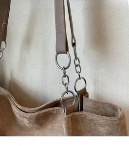 Detailed view of silver chain strap and metal rings on a brown suede tote bag