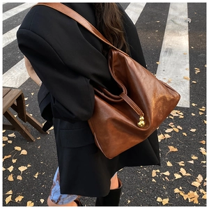Gros plan sur un sac hobo marron en cuir huilé vintage avec un pendentif gourde doré