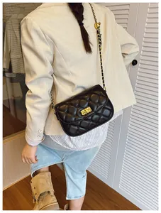 Detail shot of a black quilted crossbody bag with a gold clasp and chain strap