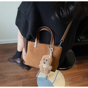 Dettaglio della borsa tote in pelle scamosciata marrone con ciondolo a forma di cane