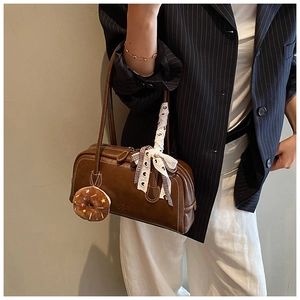 Détail du sac baguette vintage en cuir marron avec foulard en soie et pendentif donut
